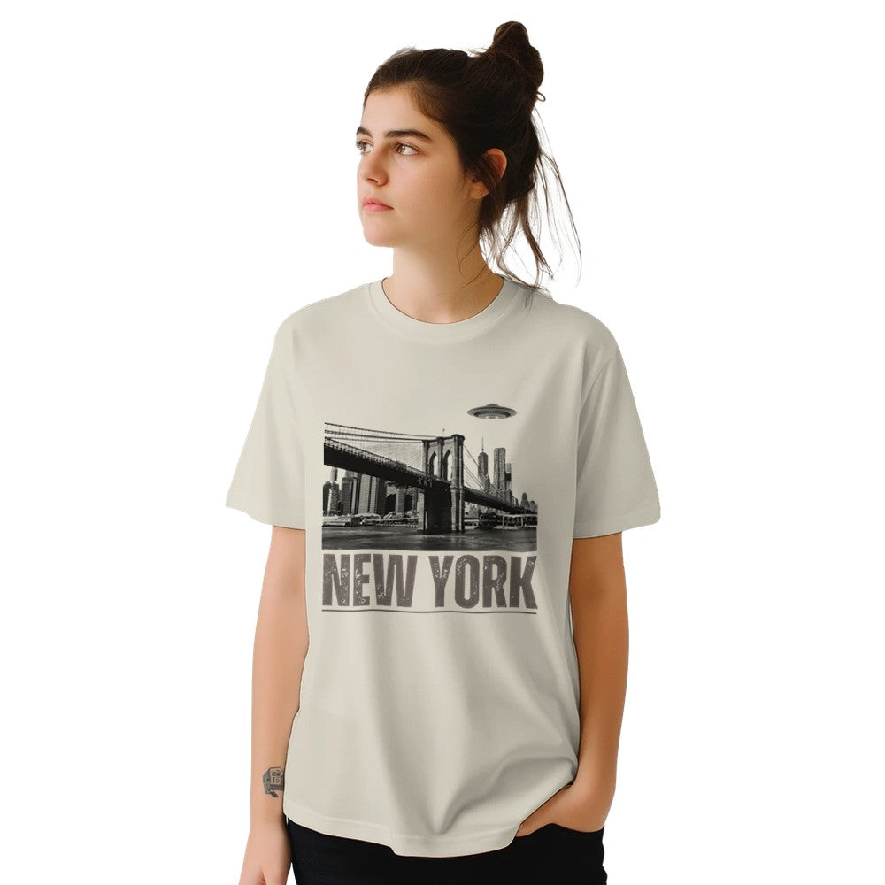 Sand colored soft casual tee showing the New York City skyline with a stylized spaceship graphic soaring above, worn by a young woman.