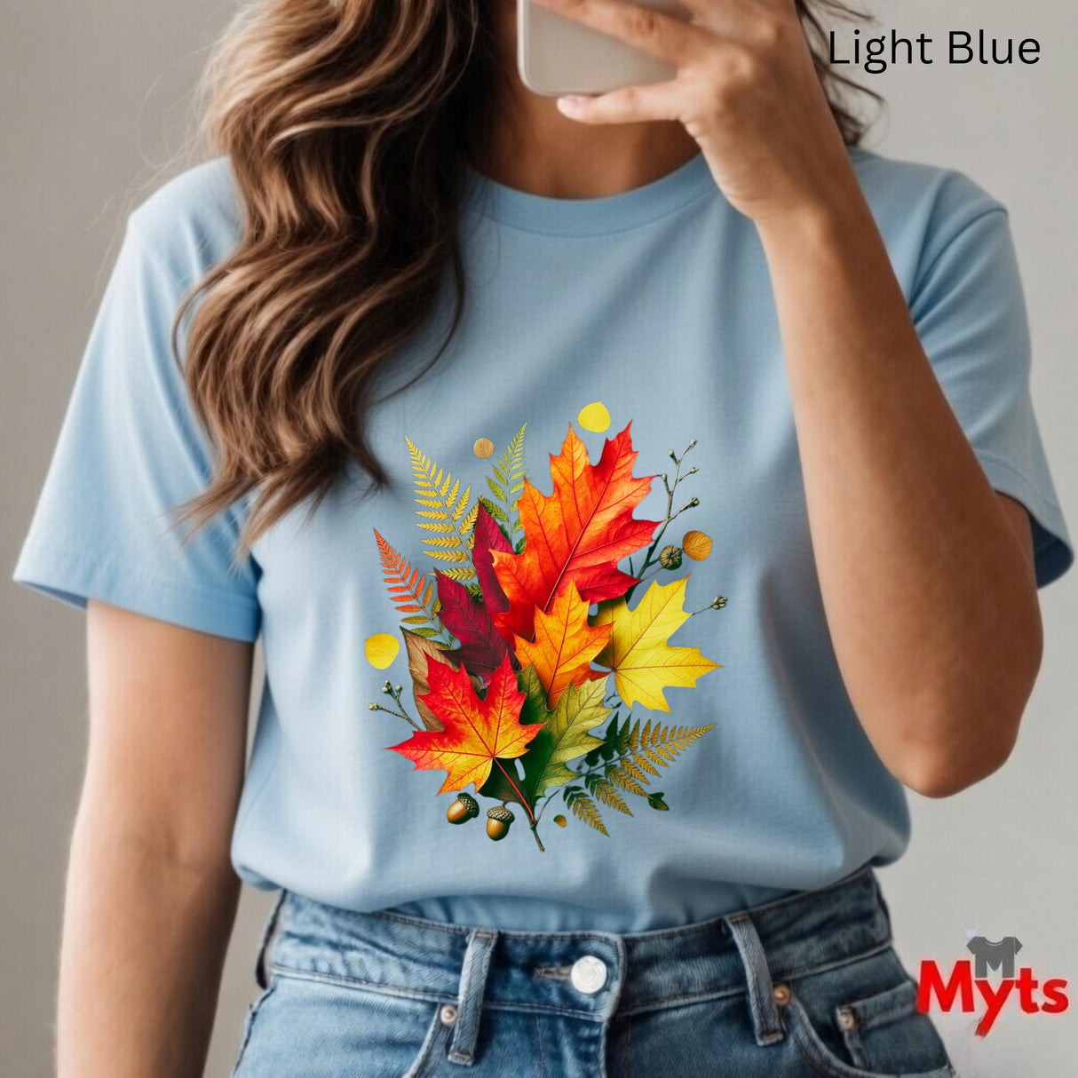 Person wearing a light blue t-shirt with a colorful leaf design, taking a selfie.