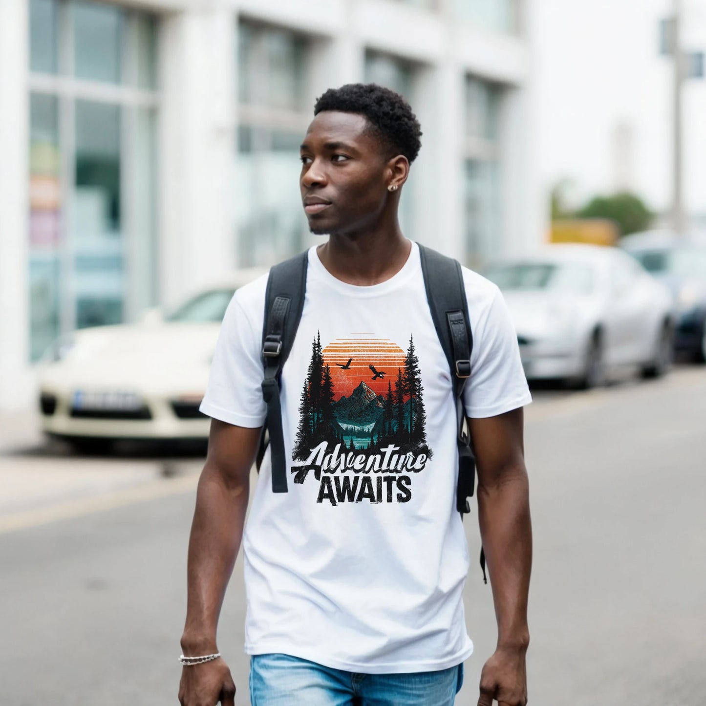 A man wearing a white t-shirt with 'Adventure Awaits' graphic and a backpack, standing on a street.