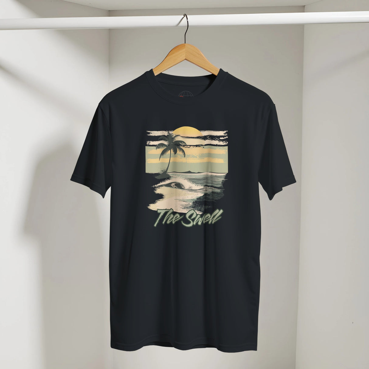 Black t-shirt with a beach graphic and 'The Shell' text on a hanger against a white wall.