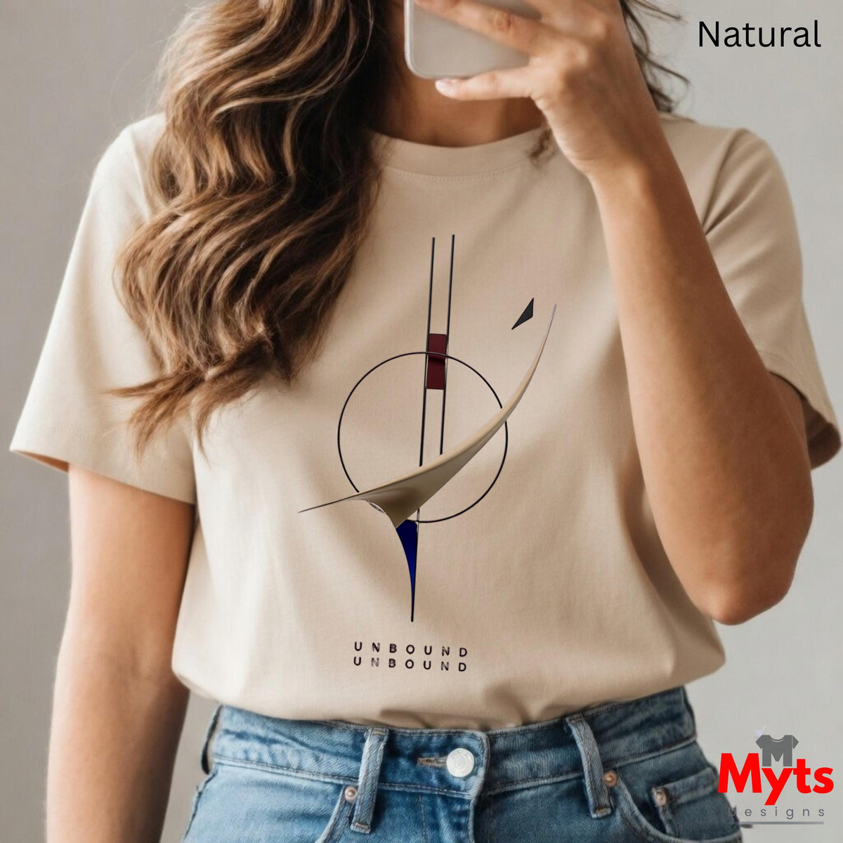 A woman wearing a Natural graphic t-shirt with a minimalist abstract design and the text 'UNBOUND UNBOUND' printed below it, paired with blue jeans. The image is a mirror selfie with the text 'Natural' in the top right corner and a 'Myts designs' logo in the bottom right.