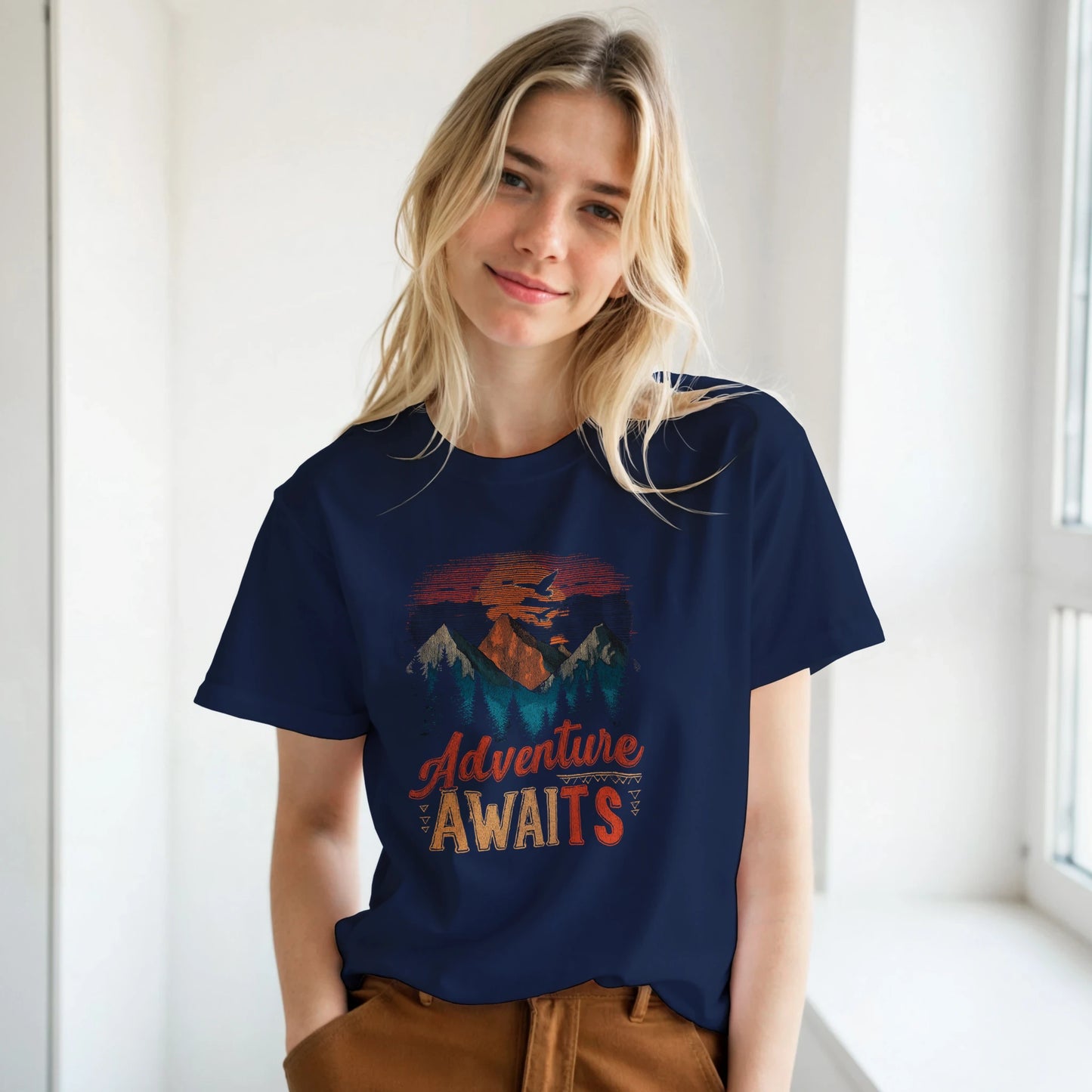 A woman wearing a navy blue t-shirt with the 'Adventure Awaits' graphic design.