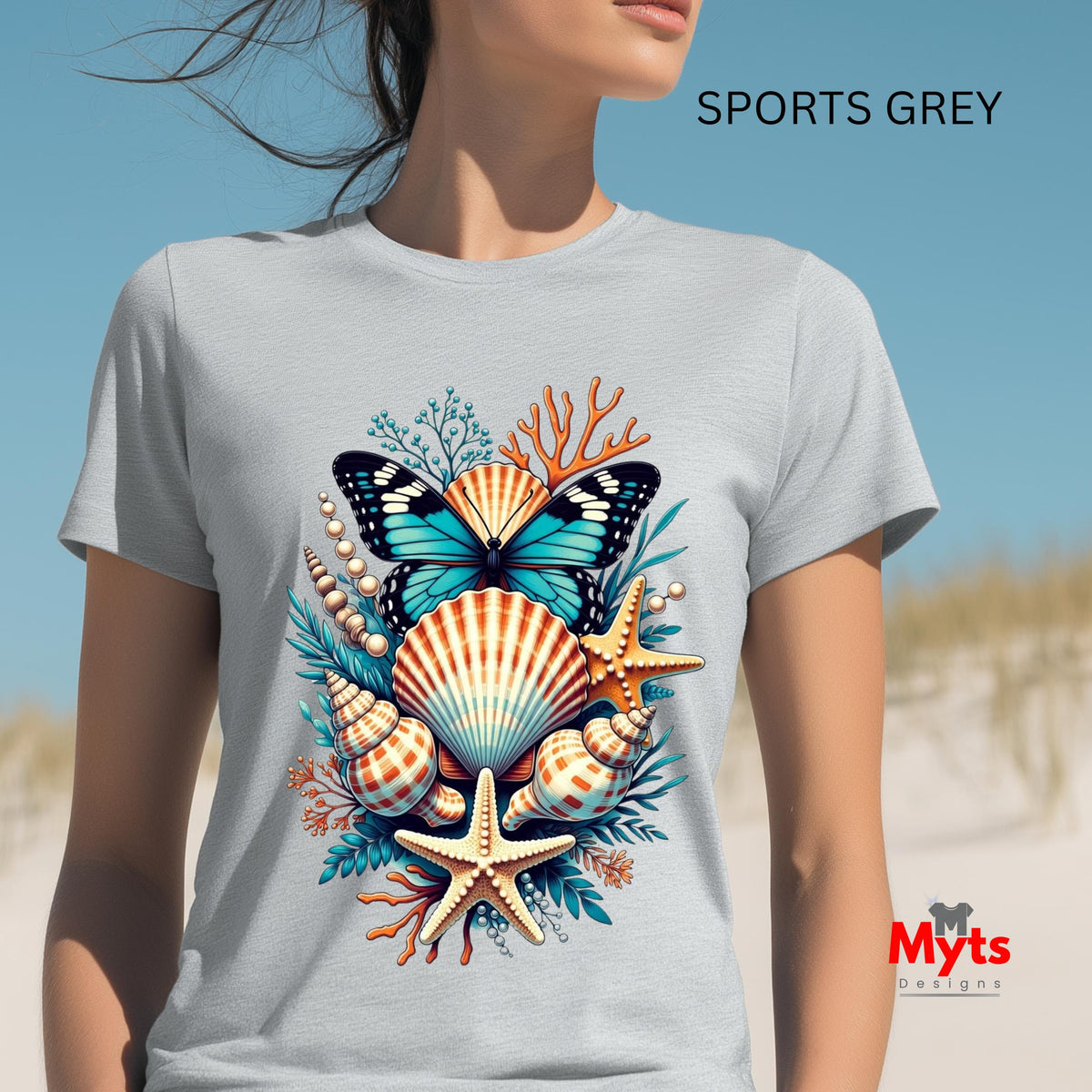 A woman wearing a light gray t-shirt with a colorful graphic of a butterfly, seashells, starfish, and coral. The text 'SPORTS GREY' is visible at the top right, and a 'Myts Designs' logo is at the bottom right.