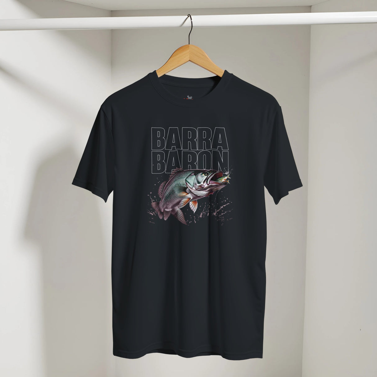 Black t-shirt with fish graphic and 'Barra Baron' text on a hanger against a white wall.