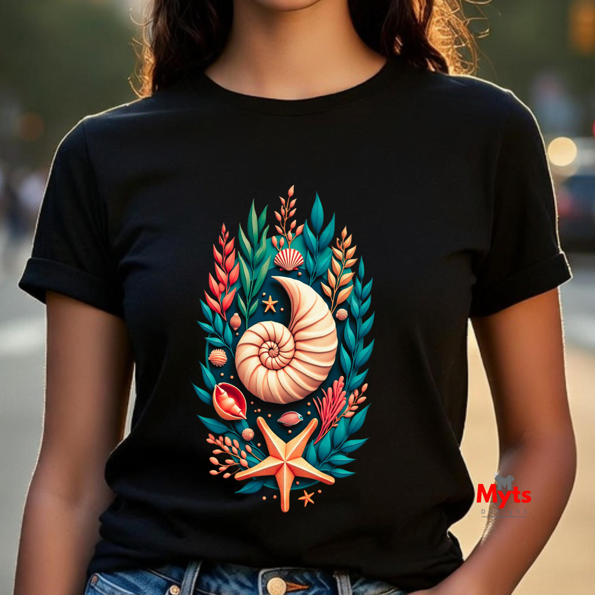 A person wearing a black short-sleeve T-shirt with a colorful seashell and sea plant graphic on the front, photographed outdoors with a blurred background.