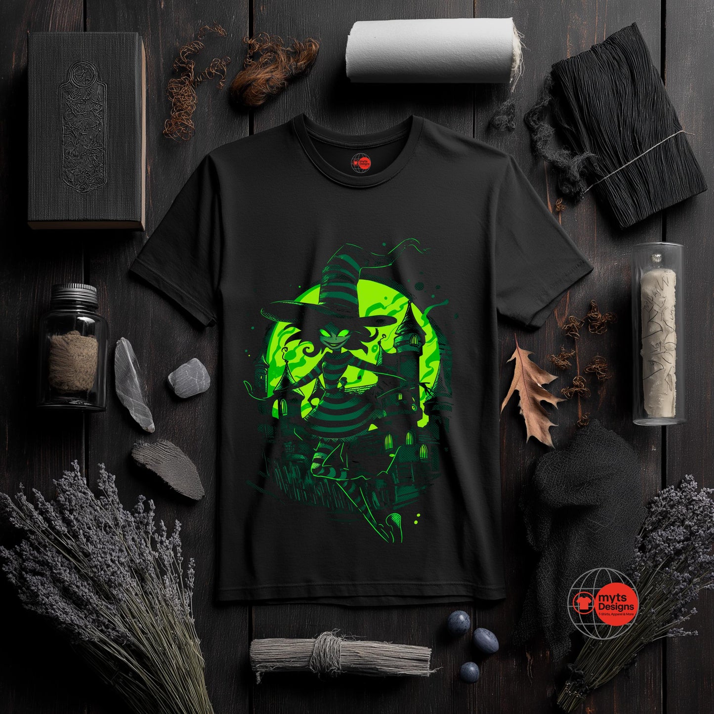 Black t-shirt with green graphic design on a dark wooden surface with various items.