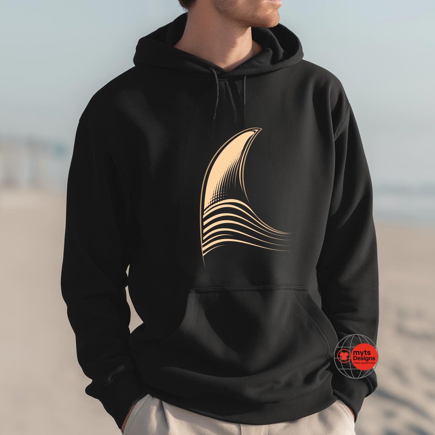 Person wearing a black hoodie with a gold abstract design on a beach.