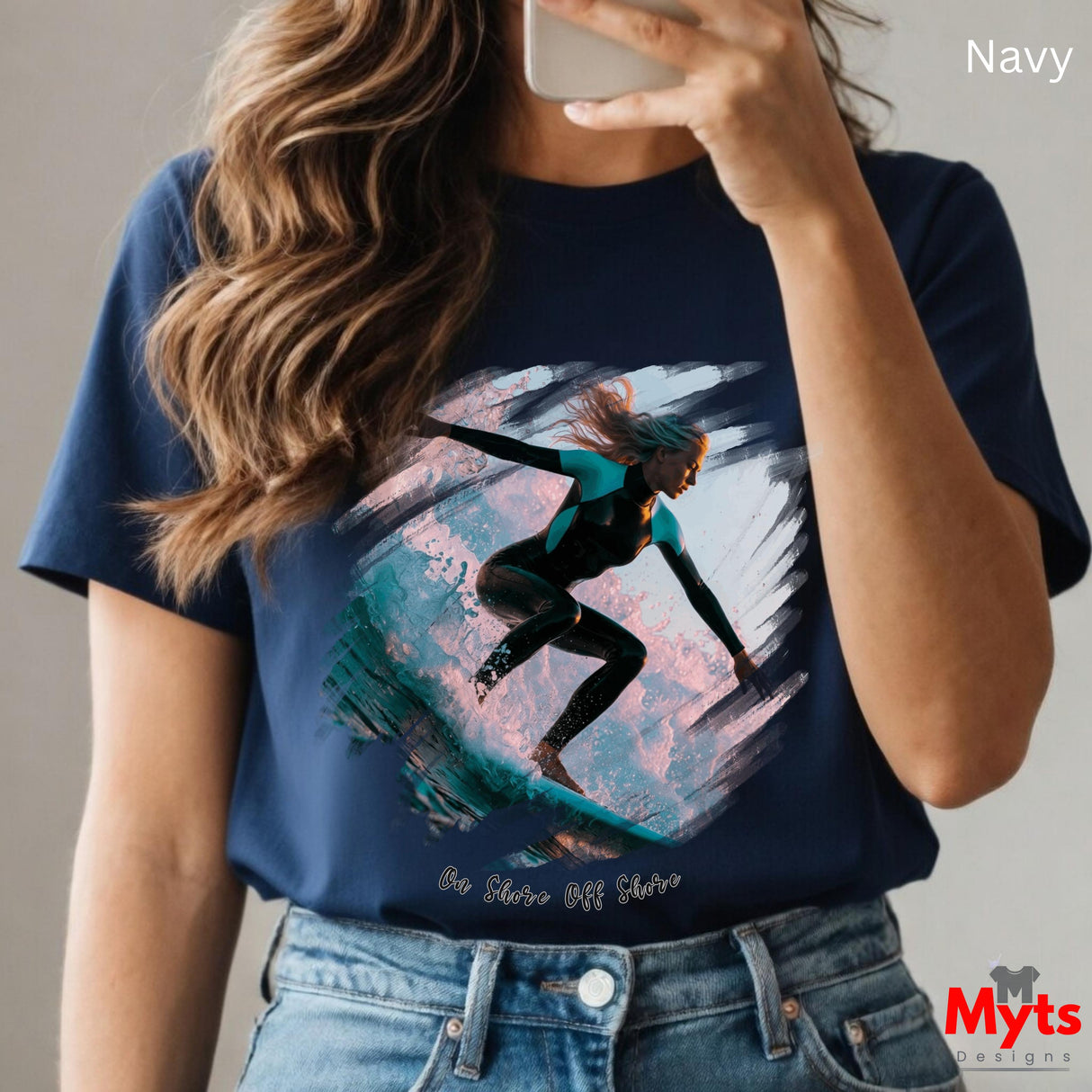 Person wearing a navy t-shirt with a graphic design of a person on a surfboard, holding a phone.