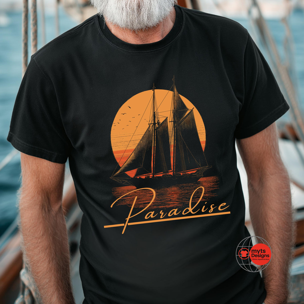 Person wearing a black t-shirt with a sailboat design and 'Paradise' text on a boat.