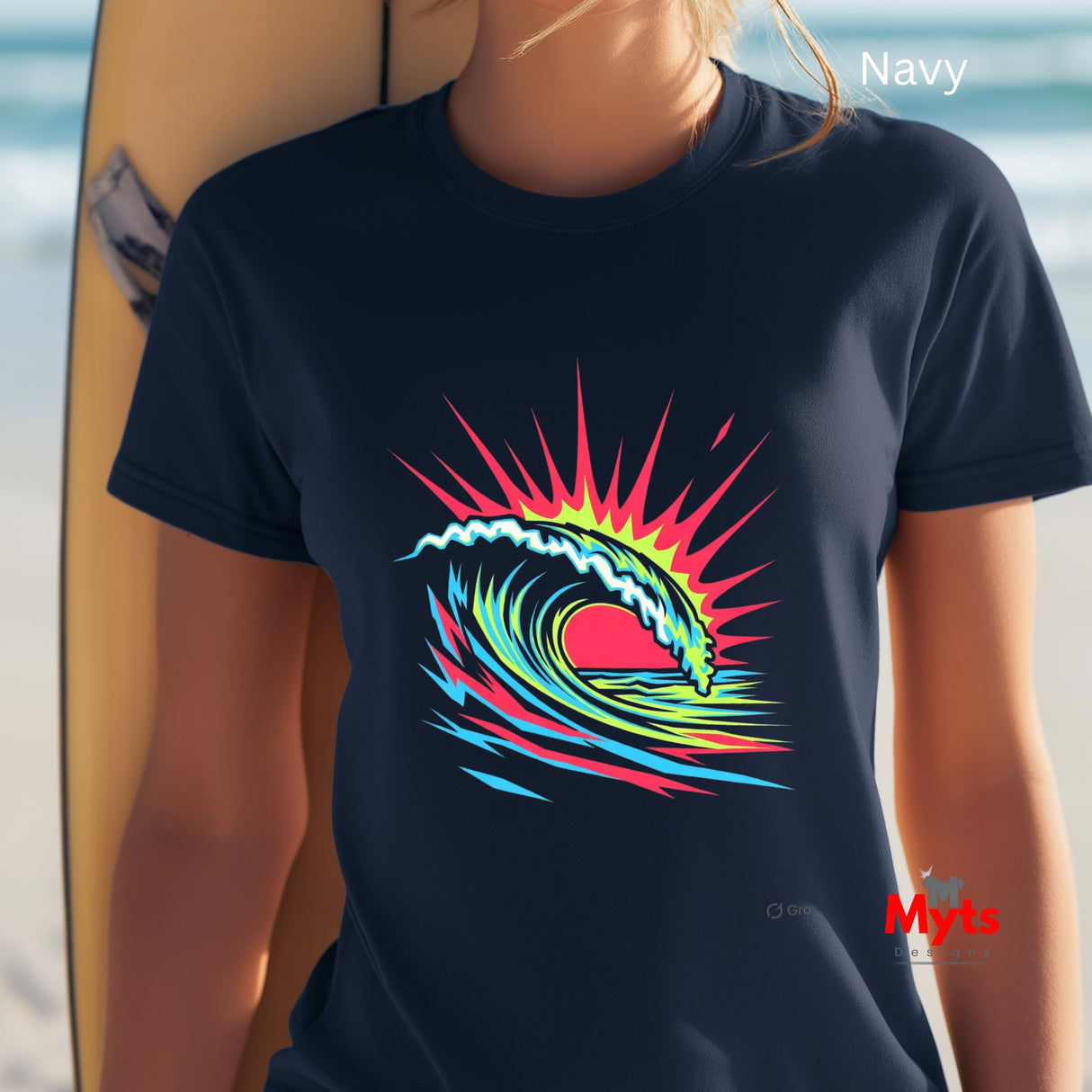 Person wearing a navy t-shirt with a colorful wave design, standing next to a surfboard on a beach.