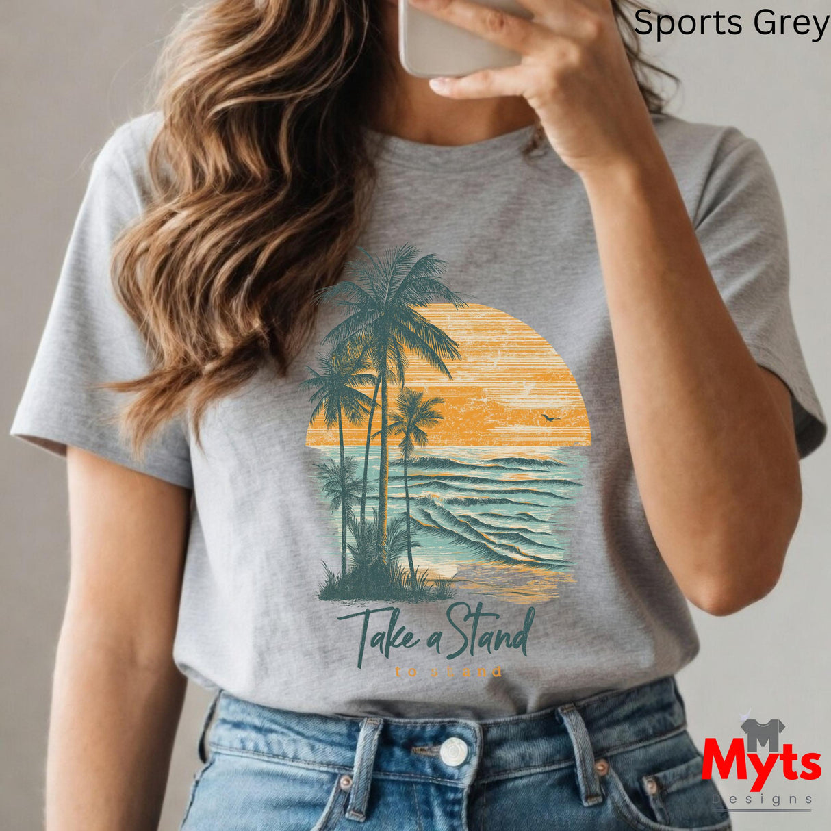 Person wearing a gray t-shirt with a palm tree and sunset design, taking a selfie.