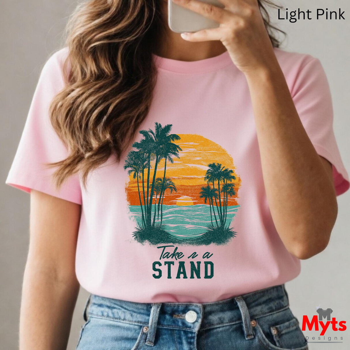 Person wearing a pink t-shirt with a palm tree design and 'Take a Stand' text, holding a phone.