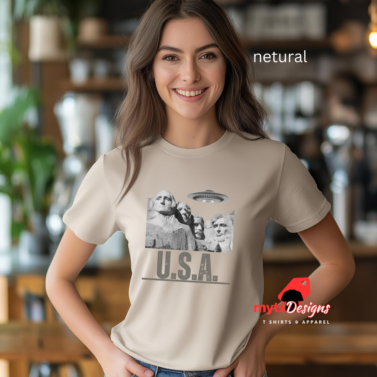 Netural colored Mt. Rushmore T-shirt, worn by a young woman in a blurred kitchen setting