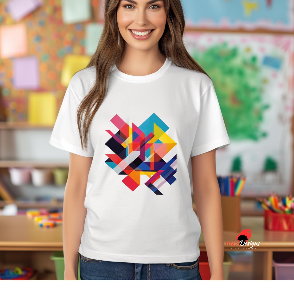 A white t-shirt features a striking, modern geometric design with overlapping vibrant shapes in shades of red, blue, yellow, pink, and black. The bold abstract pattern creates an energetic and contemporary look in the center of the shirt. The t-shirt is worn by a woman standing confidently