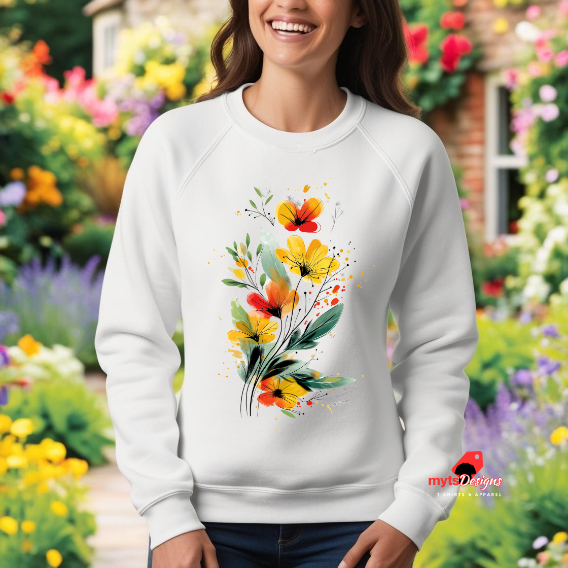 A white sweatshirt featuring an artistic watercolor floral design with red, yellow, and orange wildflowers accented by lush green leaves and delicate splatters.