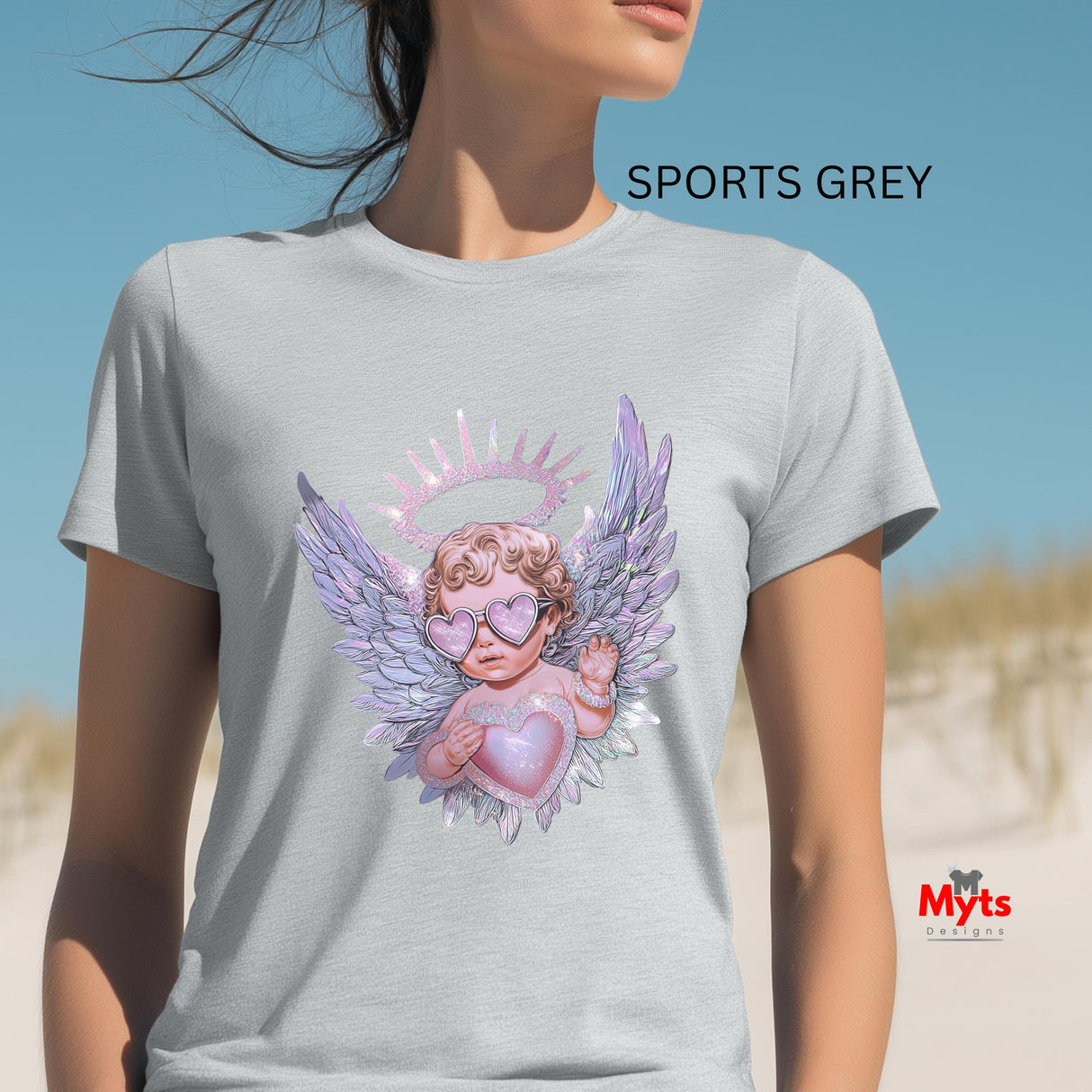 Person wearing a gray t-shirt with an angel design on a beach, featuring the brand 'Myts'.