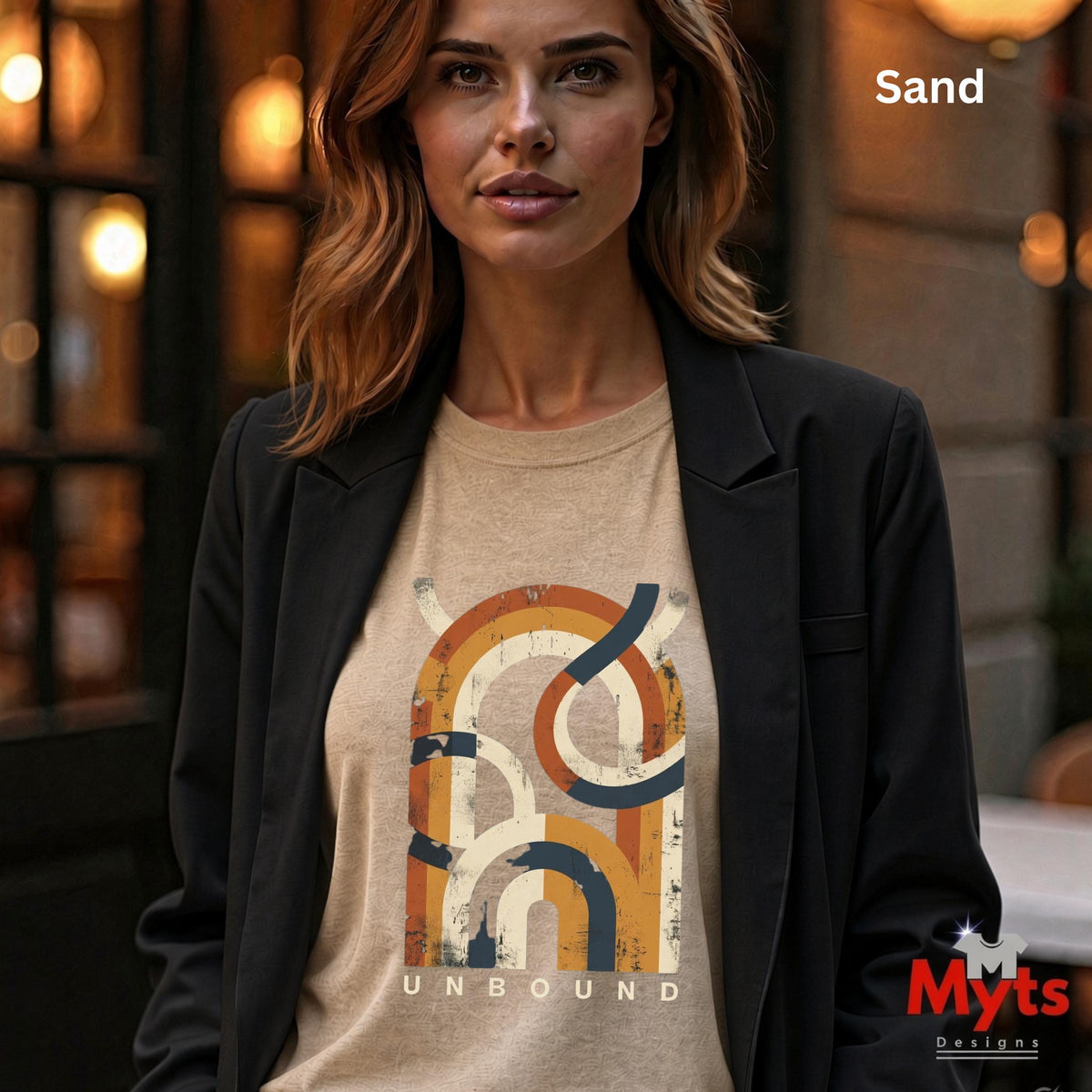 A woman wearing a Sand coloured T-shirt with a retro geometric design on the front under a black jacket