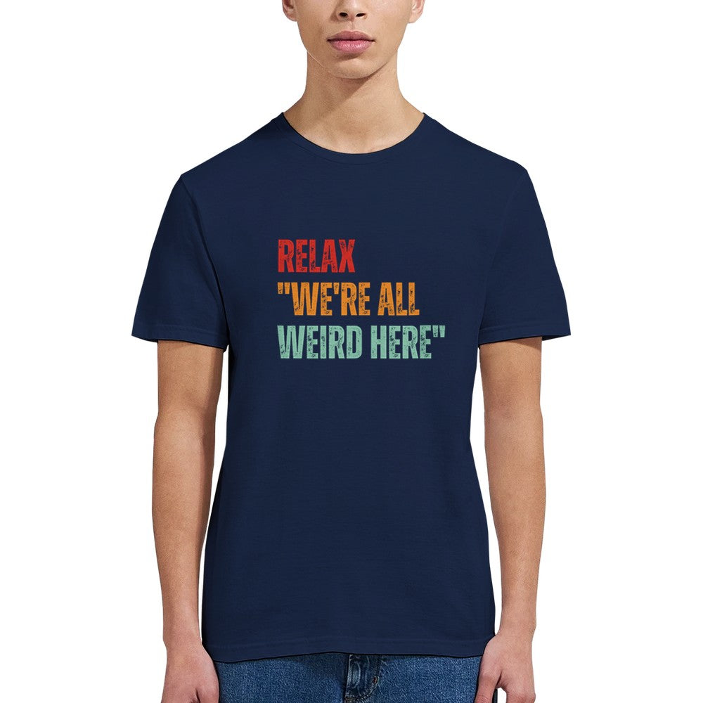 A woman wearing a navy retro-style casual tee featuring bold distressed vintage typography reading “Relax — We’re All Weird Here,” printed on ultra-soft Gildan 64000 cotton.