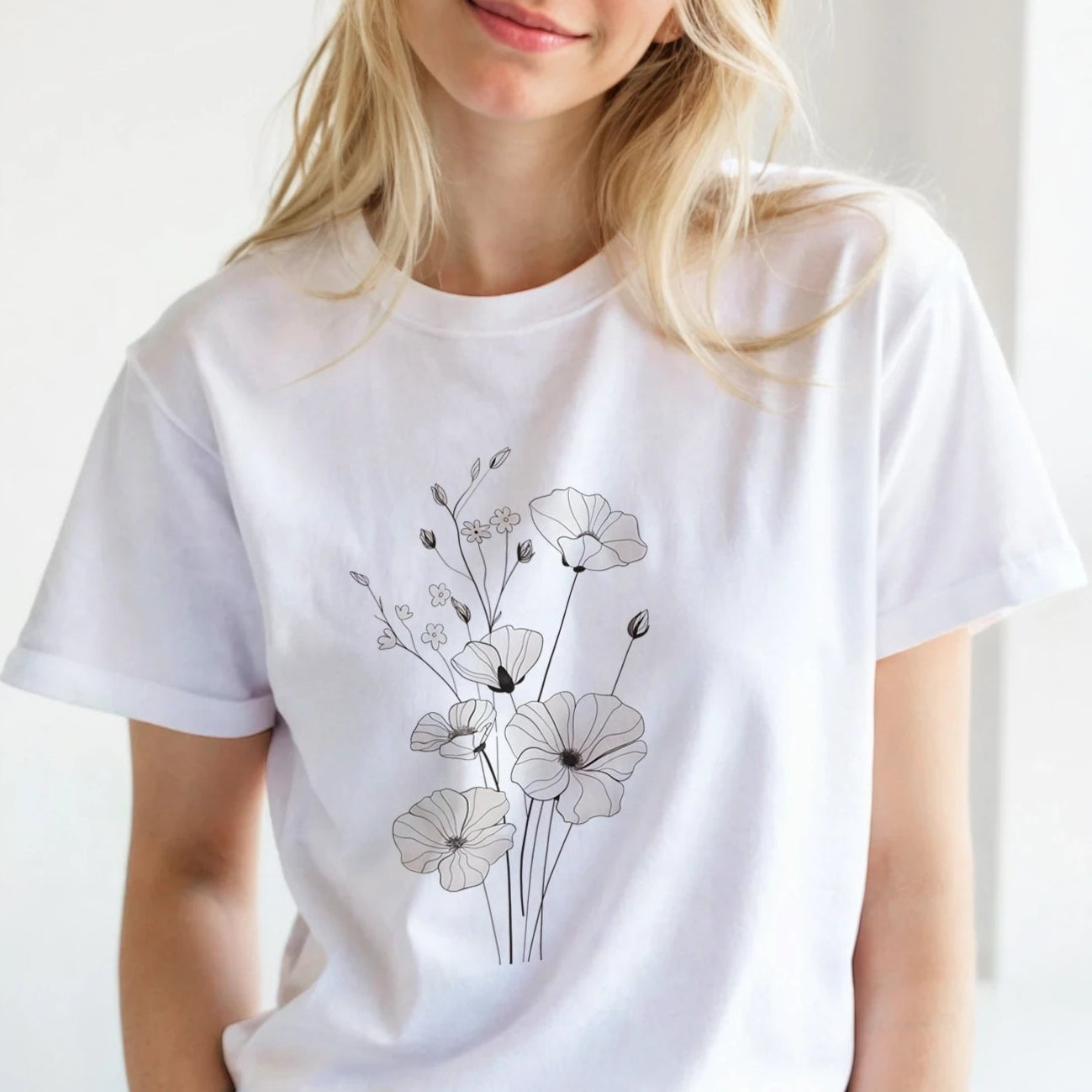 Woman wearing a white t-shirt with a floral design in a bright room.