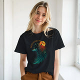 A woman wearing a black graphic t-shirt with a colorful wolf and moon design, paired with brown pants, standing in a bright indoor setting.