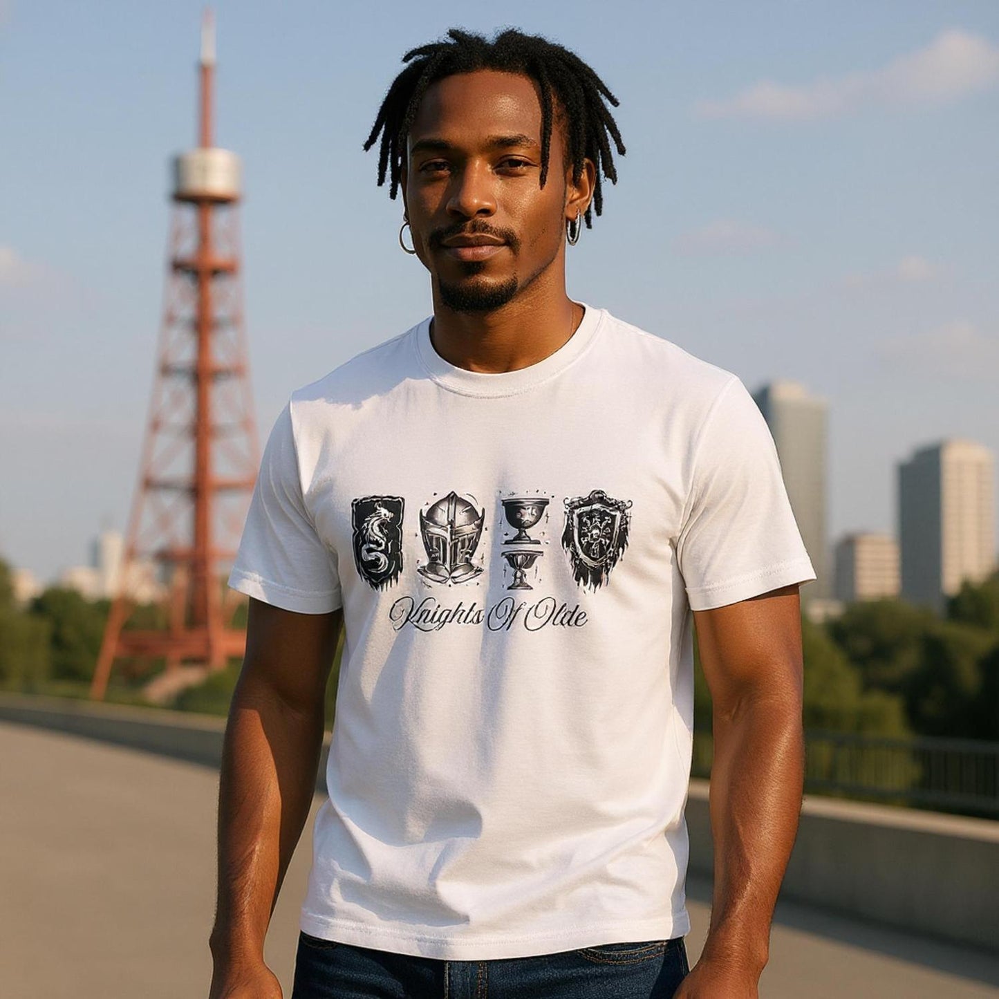 Man wearing a white t-shirt with medieval-inspired crests, helmet, goblet, and shield graphic design with the text “Knights of Olde.” Perfect for history buffs and fantasy fans.