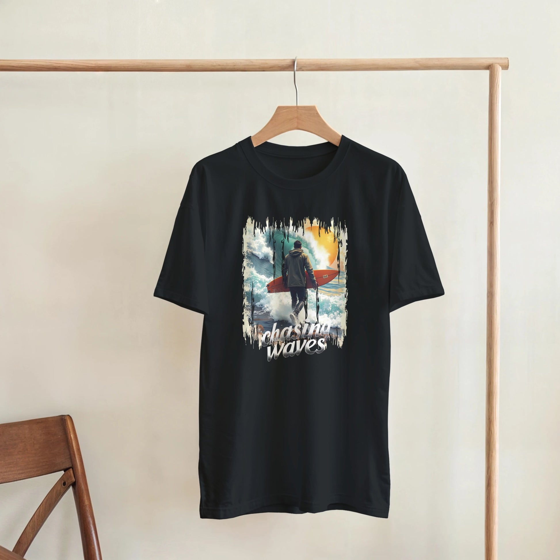 Black t-shirt with a graphic design of a person with a surfboard and 'Plashing Waves' text, hanging on a wooden rack.