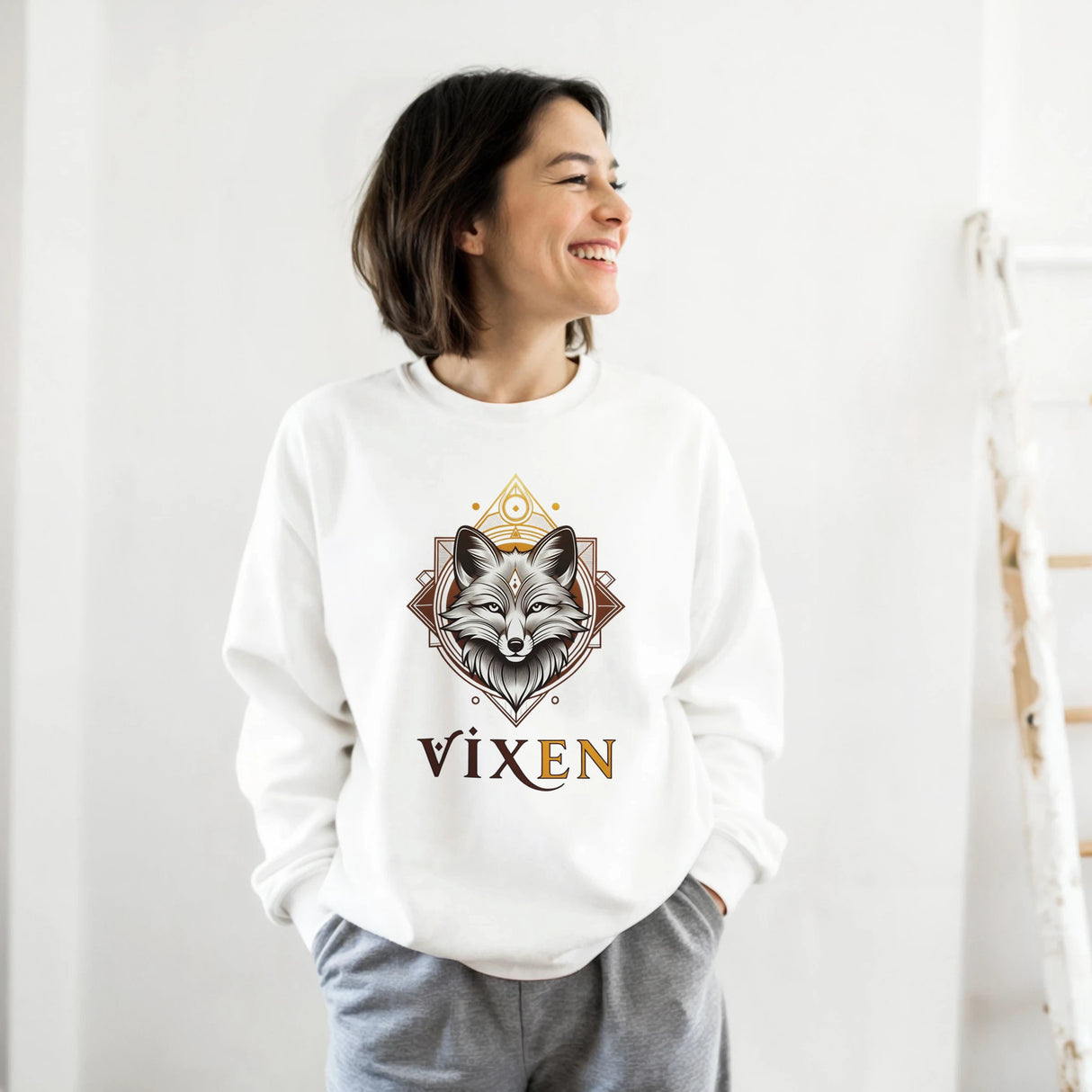 Person wearing a white sweatshirt with a fox design and 'Vixen' text on a plain background