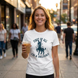 Woman holding a coffee cup on a city street wearing a white t-shirt with a graphic and text.