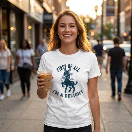 Woman holding a coffee cup on a city street wearing a white t-shirt with a graphic and text.