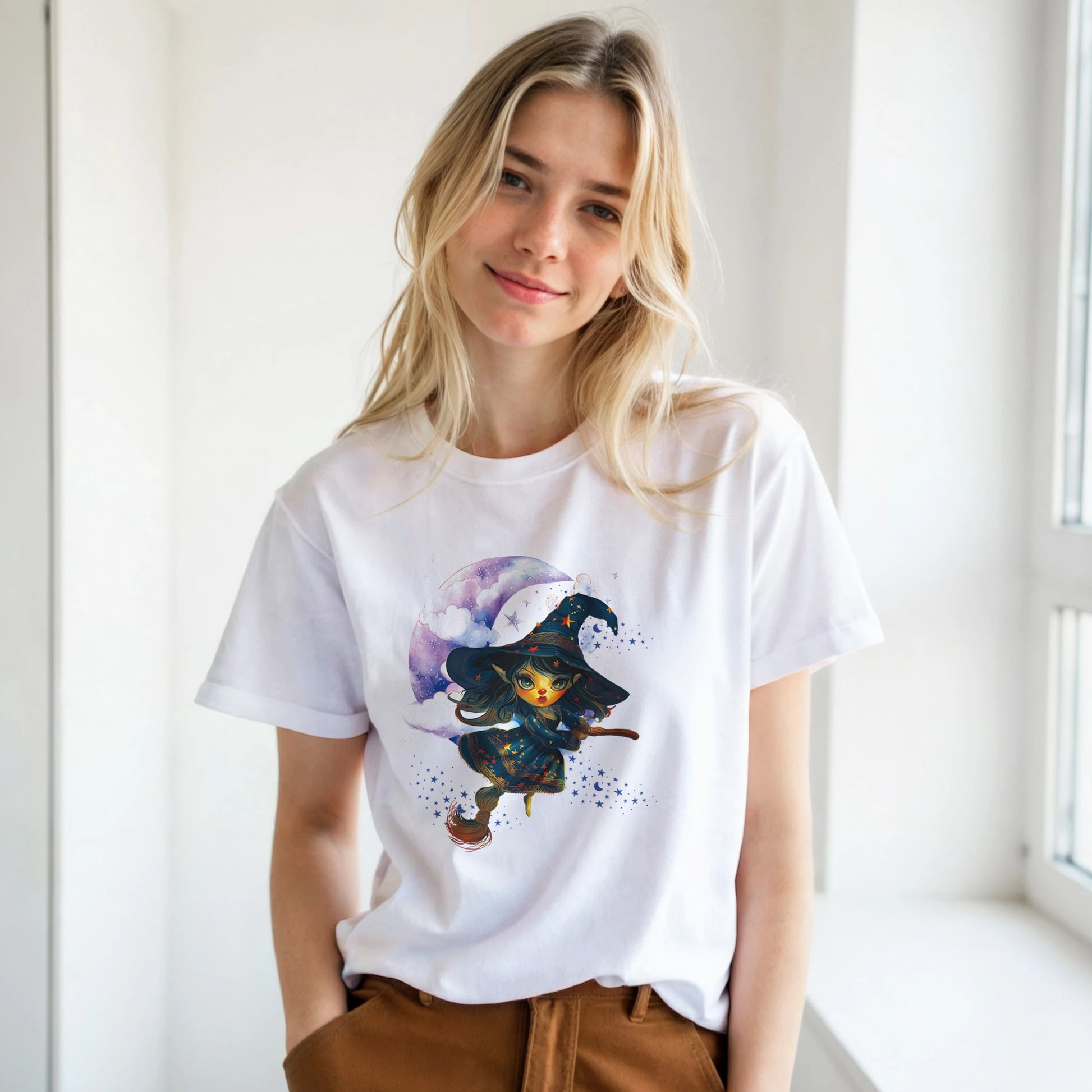 Person wearing a white t-shirt with a graphic design of a witch and galaxy.