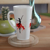 A white ceramic latte mug with a black and red ballet dancer silhouette design, resting on a round wooden coaster on a wooden table next to a small potted cactus.