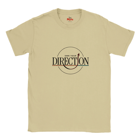A Sand crewneck T-shirt featuring a graphic print on the chest that reads 'OWN YOUR DIRECTION' with an arrow and circular design, on a solid white background.