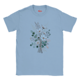 A light blue short-sleeve crewneck t-shirt featuring a central graphic of a watercolor-style floral bouquet with green, white, and peach blossoms. The brand name 'Myts' is printed in red on the inside neck label.