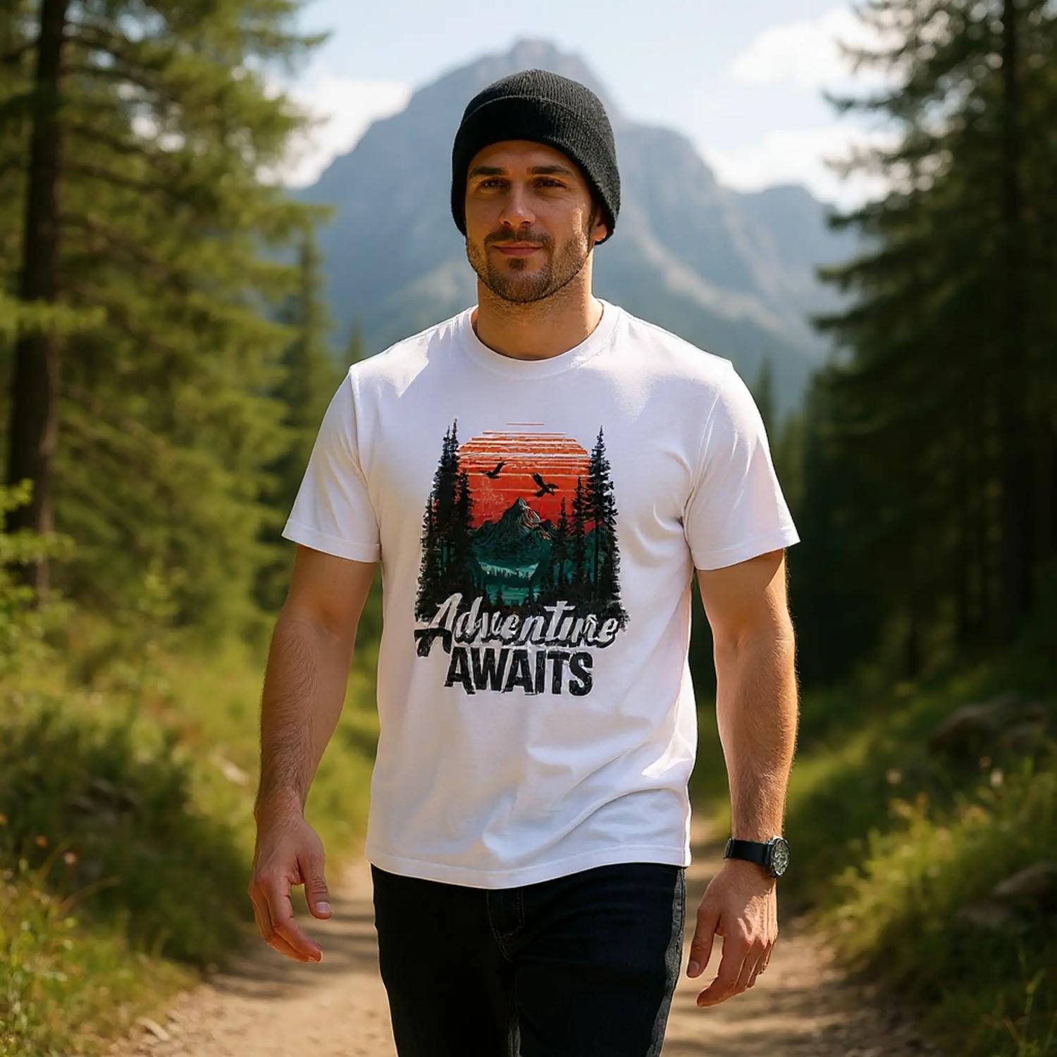 Man wearing a 'Adventure Awaits' t-shirt in a forest setting with mountains in the background