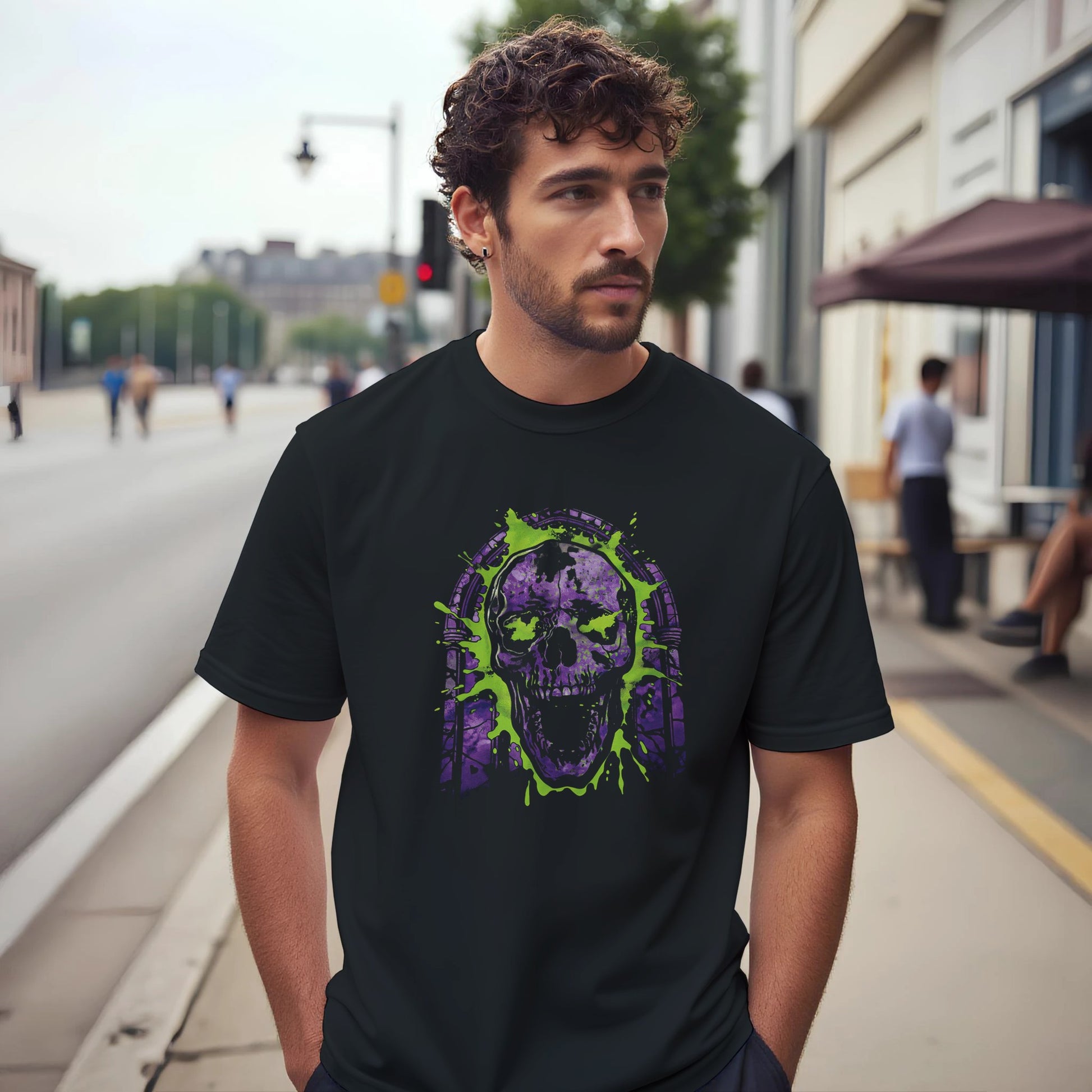 A man wearing a black t-shirt with a purple and green skull design on a city street.