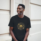 Man wearing a black t-shirt with a gold and bronze circular design, standing against a neutral background.