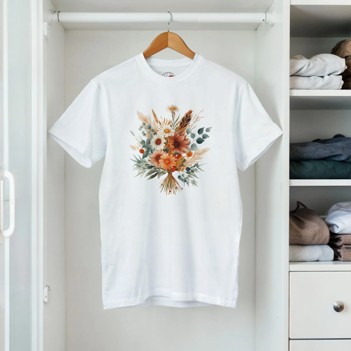 A white t-shirt with a floral design on a hanger in a closet.
