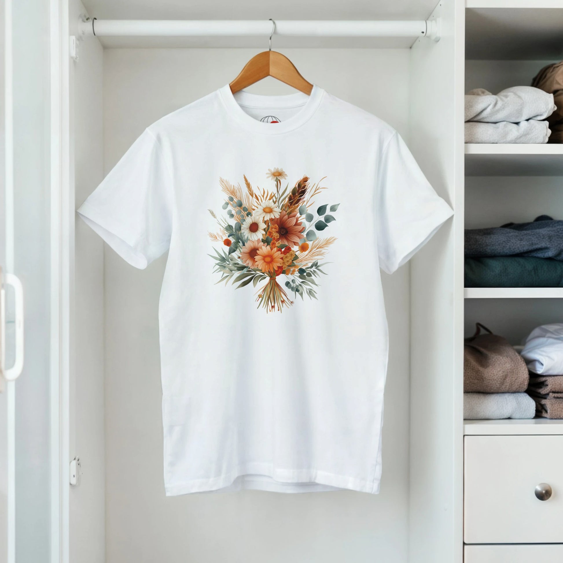 A white t-shirt with a floral design on a hanger in a closet.