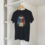 Black t-shirt with a colorful graphic design on a hanger against a white wall.