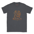 A dark heather gray crewneck t-shirt featuring a distressed orange graphic of a koala sitting on a branch with the text 'KOALA LIVE GENTLY' printed on the chest.