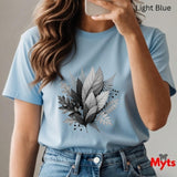 Person wearing a light blue t-shirt with leaf design, holding a phone.