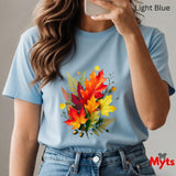 Person wearing a light blue t-shirt with a colorful leaf design, taking a selfie.