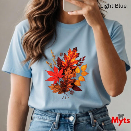 Person wearing a light blue t-shirt with autumn leaf design, taking a selfie.