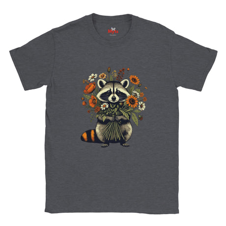 A dark heather gray t-shirt featuring a graphic of a raccoon holding a bouquet of orange, yellow, and white wildflowers. The neck label shows the brand 'The Happy Camper'.