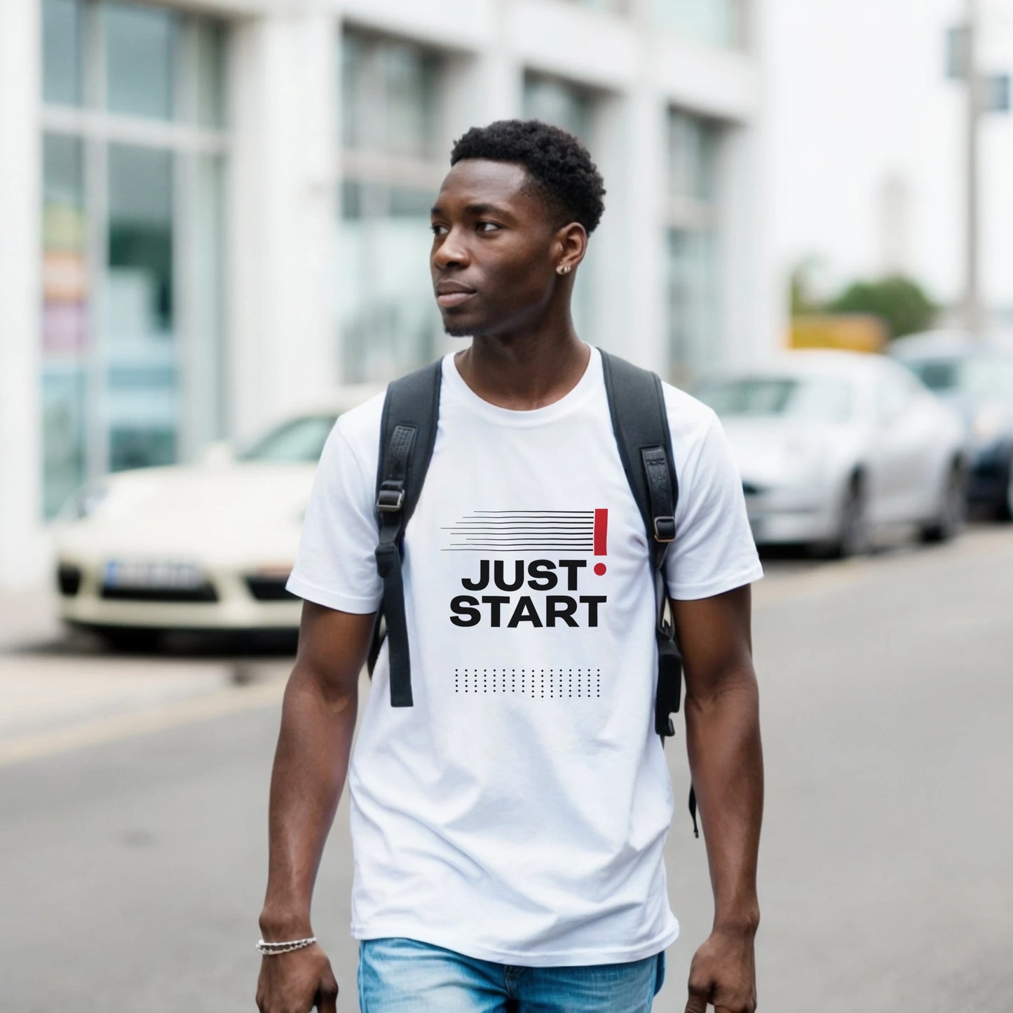Man wearing a white t-shirt with 'JUST START' text on a street.