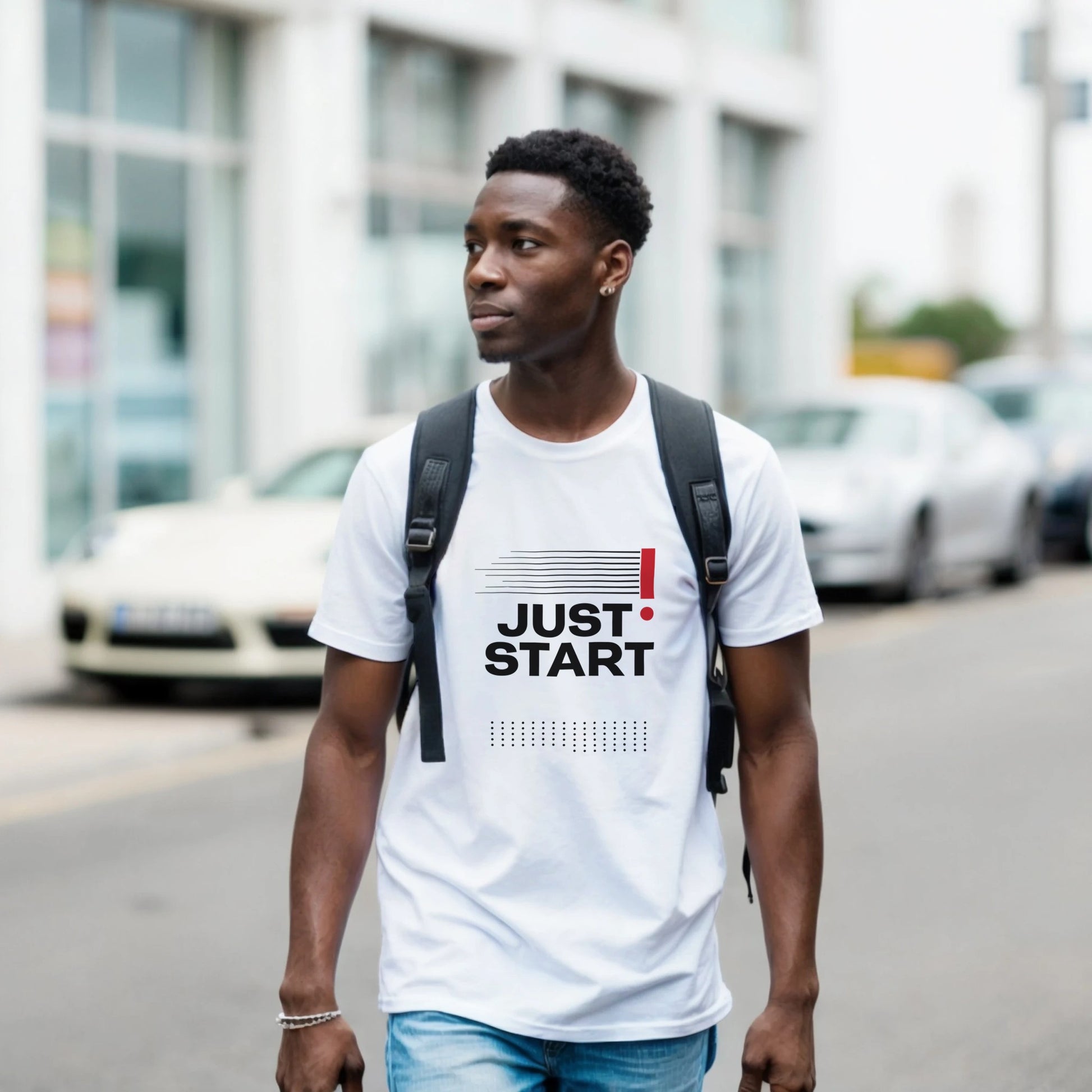 Man wearing a white t-shirt with 'JUST START' text on a street.