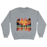A grey unisex sweatshirt featuring a vibrant tropical sunset design with silhouettes of surfers walking along a beach. The graphic includes palm trees, an orange and pink sky, and artistic brushstroke edges, creating a modern coastal vibe. Ideal for beach lovers, surfers, and casual fashion fans.

