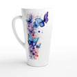 A tall white ceramic latte mug featuring a watercolor-style print of blue and purple butterflies with splashes of red and purple paint on the side, set against a plain white background.