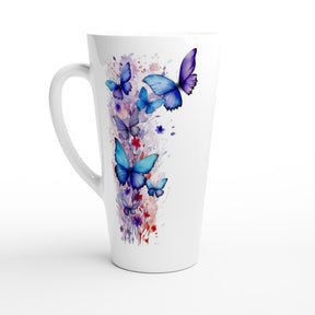 A tall white ceramic latte mug featuring a watercolor-style print of blue and purple butterflies with splashes of red and purple paint on the side, set against a plain white background.