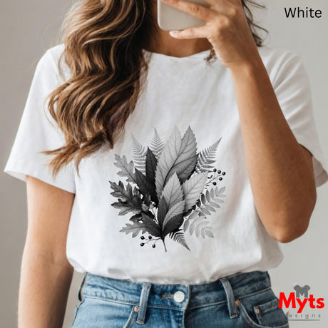 Person wearing a white t-shirt with leaf design, holding a phone.